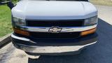 A 2011 Chevrolet Express with a silver grille and black mesh, featuring a prominent Chevrolet bowtie emblem in the center