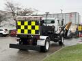 A 2016 Freightliner 108SD truck equipped with a plow and a rear-mounted sign featuring a black and yellow checkered pattern