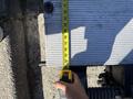A person holds a measuring tape against a flat surface of a 2015 Freightliner M2 106 showing measurements along the edge