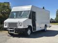 A white 2019 Freightliner MT45 box truck with an open driver's side door parked on a road