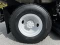 Close-up of a large black tire with deep treads mounted on a white rim belonging to a 2012 Autocar Xpert