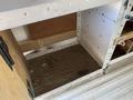 An empty metal storage compartment inside a 2012 GMC Savana van with a wooden floor and a small carpeted area