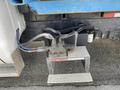 A hydraulic pump assembly mounted on a sturdy platform with hoses connected to it situated near the rear of a 2002 Ford F-550