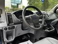 Interior view of a 2017 Ford Transit 350 featuring a steering wheel dashboard control panel and central console with storage compartments