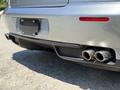 A silver 2005 Ferrari 612 Scaglietti showcasing its rear design with dual exhaust pipes and sleek lines