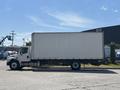 A 2015 Freightliner M2 106 truck with a white box cargo area parked in a lot facing right