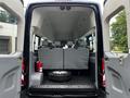 A 2017 Ford Transit 350 with its rear doors open showcasing an empty cargo area featuring a spare tire and seating configuration for multiple passengers