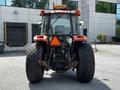 A red 2011 Kubota M8540D tractor facing forward with large rear tires and a triangular warning sign mounted on the back