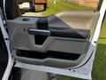 A close-up of the driver's side door panel of a 2021 Ford F-550 featuring a gray armrest and control buttons