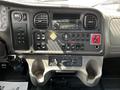 The dashboard of a 2012 Freightliner M2 106 featuring various control buttons gauges and a radio display