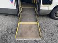 A metallic wheelchair ramp extended from the open doors of a 2012 Chevrolet Express van