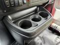 A black plastic cup holder with three circular compartments designed for holding drinks in a vehicle interior