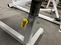 Close-up of a gym equipment leg with an adjustable yellow knob for securing height settings on a fitness station