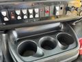 A black console with three cup holders and control buttons for various functions in a 2017 Chevrolet Express