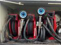 Three red hose reels with black hoses and pressure gauges mounted inside a compartment of a vehicle