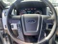 Steering wheel of a 2014 Ford F-150 featuring controls for audio and cruise settings with the Ford logo in the center