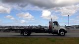 A 2015 International DuraStar 4300 truck in profile view with a flatbed and red hydraulic lift gate