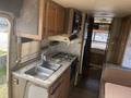 Interior view of a 1987 Chevrolet Fleetwood Pace Arrow featuring a compact kitchen with a sink a stove and wooden cabinetry