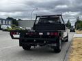 A 2020 Ford F-350 pickup truck with a flatbed and black tool racks is parked on a street
