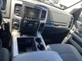The interior of a 2015 RAM 1500 featuring a touchscreen display on the dashboard several control buttons and a center console with cup holders and storage compartments
