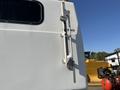 A 2014 Ford F-350 SD with a white exterior featuring a side view of the vehicle’s rear door and a metal latch mechanism mounted on the door