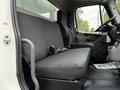 The interior of a 2018 Freightliner M2 106 featuring a black bench seat with seatbelts and a driver's seat positioned next to it