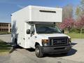 A 2012 Ford Econoline E-450 with a boxy white delivery truck body and a raised cargo area on the roof