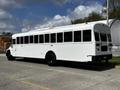 A 2022 Blue Bird BB Conventional bus in white with black wheels and multiple windows on the side