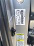 A metal plate featuring vehicle information, including a barcode and various safety labels, attached to the door frame of a 2017 Acura TLX