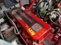 Red engine cover labeled with "CUMMINS" on a Freightliner M2 106 with visible hoses and wiring attached to the engine components
