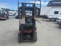A 2010 Toyota 7FGGU25 forklift facing forward with its forks elevated and the rear engine compartment visible