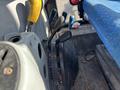 Control levers and dashboard of a 2010 New Holland T4050 tractor with a blue seat visible in the foreground