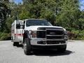 A 2009 Ford F-550 truck with a white body and a silver tool bed visible in the foreground