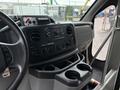 Interior dashboard of a 2014 Ford E-350 featuring controls for audio and climate along with cup holders and various switches
