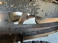 Underneath a 2016 Ford F-250 SD showing parts of the frame suspension components and exhaust system with some surface rust and dirt visible on the metal surfaces