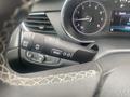 A close-up view of the steering wheel controls and instrument panel of a 2018 Buick Encore showing various control buttons and a speedometer