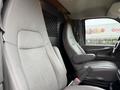 Interior of a 2014 GMC Savana with gray leather seats and a partition wall separating the driver area from the cargo space