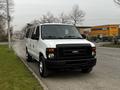 A 2011 Ford Econoline van in white with black accents parked on a street