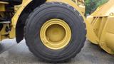 A large tire of a 2019 Caterpillar 972M XE heavy equipment vehicle with visible tread patterns and a yellow rim