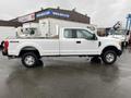 A white 2017 Ford F-250 SD truck with a flatbed and four-wheel drive parked on a wet surface