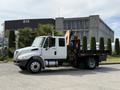 A 2011 International 4300 truck with a flatbed and an orange crane attachment on the side