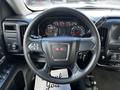 A 2017 GMC Sierra 1500 steering wheel with the GMC logo in the center and a dashboard displaying various gauges and controls