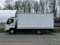 A 2013 Hino 195 truck with a white delivery box body and red stripes on the sides facing left