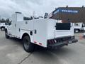 White 2003 Ford F-450 SD work truck with a utility bed and rear equipment storage compartments