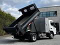 A 2015 Mitsubishi Fuso FE dump truck with the bed raised, highlighting its cargo area and rear chassis design