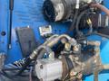 Close-up of hydraulic components and control panel on a 1997 Genie S-65 4X4 with blue paint and various hoses and fittings visible