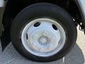 A close-up of a white wheel on a 2016 Isuzu NPR featuring six lug nuts and a black tire with a visible tread pattern
