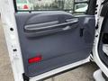 The interior door panel of a 2001 Ford F-350 featuring a gray plastic handle a black speaker grille and a textured armrest