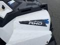 A close-up of a 2017 Polaris Scrambler showcasing the "On Demand AWD" label with a blue accent on a white panel covered in droplets of water