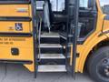 A 2007 Freightliner B2 school bus with an open door showing steps leading up to the driver's area and a mobility aid symbol on the exterior